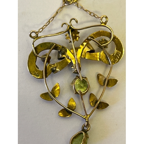 114 - An Edwardian 9ct gold lavalier pendant designed as a bow with leaf garland, set with  peridot stones... 