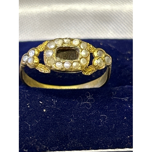 145 - A Georgian  gold mourning ring, likely 18ct, with plaited hair central panel surrounded by natural p... 