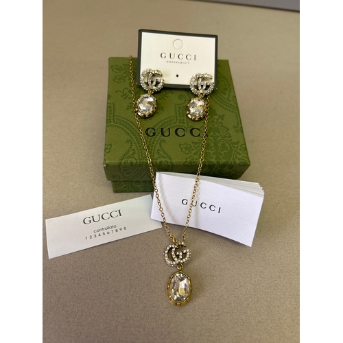 47A - Gucci. Designer double G necklace and matching earring set with large oval cut white crystals and wi... 