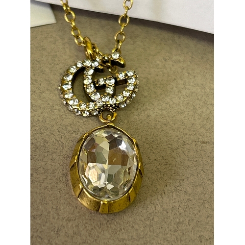 47A - Gucci. Designer double G necklace and matching earring set with large oval cut white crystals and wi... 