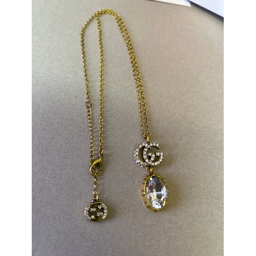 47A - Gucci. Designer double G necklace and matching earring set with large oval cut white crystals and wi... 
