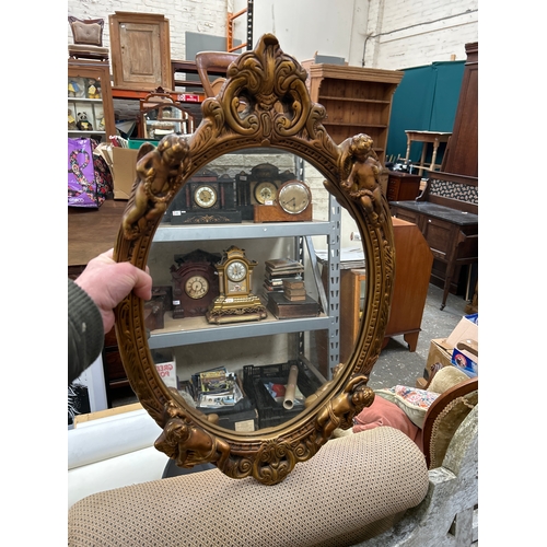 231 - Vintage gilt framed oval wall mirror in the rococo style with four cherubs adorning the frame. 64cm ... 