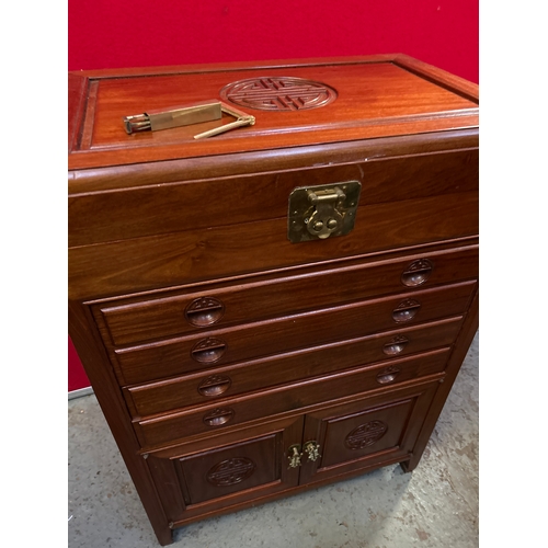 595 - A Chinese hardwood side cabinet with hinged top, four slim drawers and cupboard below. Carved to the... 