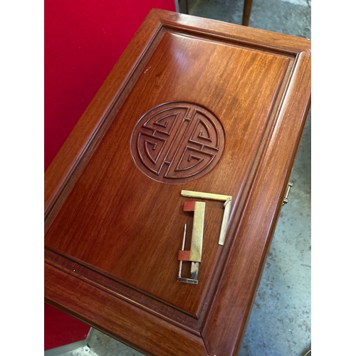 595 - A Chinese hardwood side cabinet with hinged top, four slim drawers and cupboard below. Carved to the... 