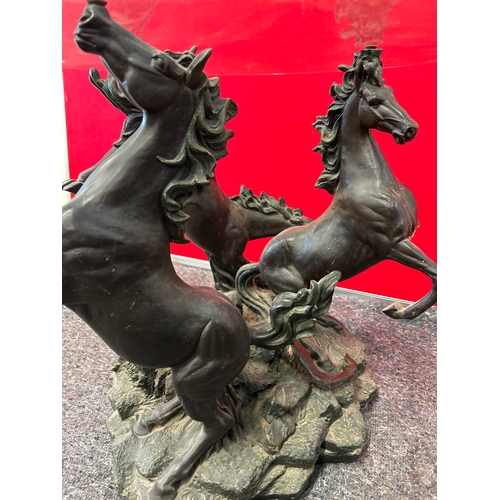599 - A 20th Century circular glass topped coffee table with the base in the form of three rearing horses.... 