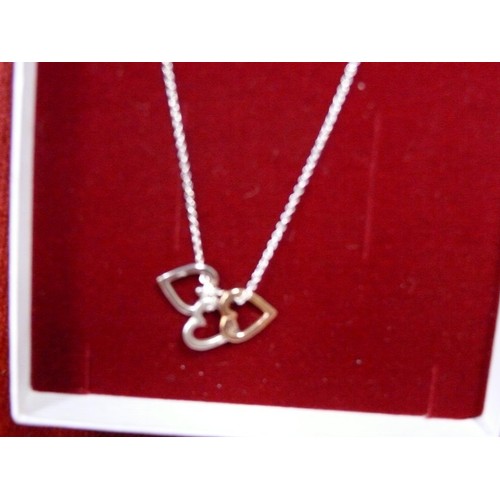 19 - A SOLID SILVER CHAIN WITH 3 HEARTS ON IT
