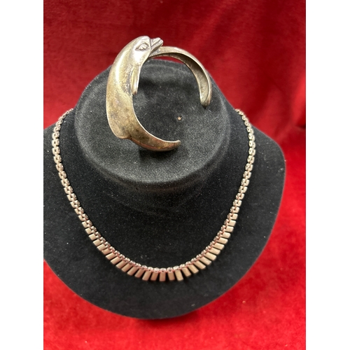 76 - Heavy sterling silver dolphin bangle and a sterling silver Cleopatra necklace. Total weight 75 grams