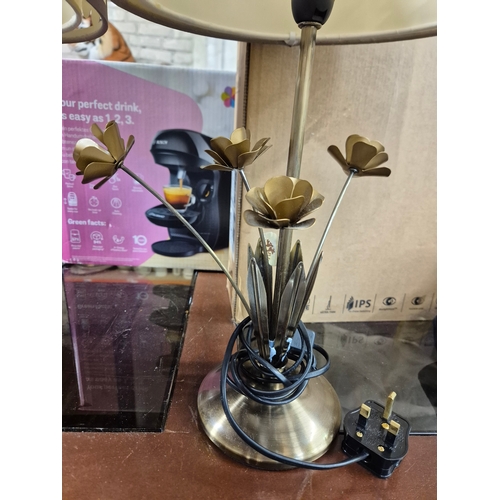 223 - Pair of table lamps with a cut-out floral pattern shades and metal bases with decorative leaves. 