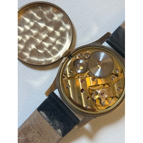27 - 9ct gold wrist watch by Garrard on leather strap, working when lotted. Presentation inscription to b... 