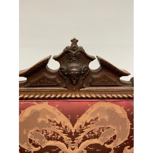 253 - A pair of antique carved arm chairs with oak leaf design, upholstered with burgundy damask