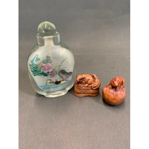 38 - An oriental glass bottle with two carved netsukes