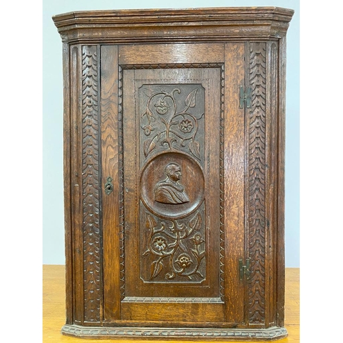 123 - An antique oak corner cupboard with carved design of gentleman with flowers and leaves, possibly 18t... 