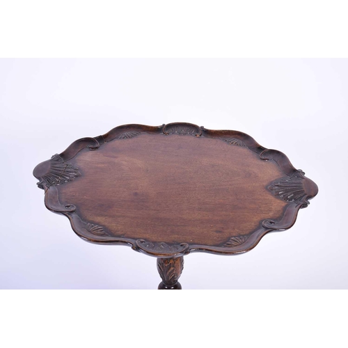 115 - An early 20th century Geo III mahogany tripod table, the shaped top with shell and scroll borders, o... 