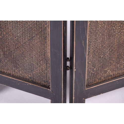 132 - A four fold room divider/screen, with ebonised frame enclosing woven wicker panels, with brass cappe... 