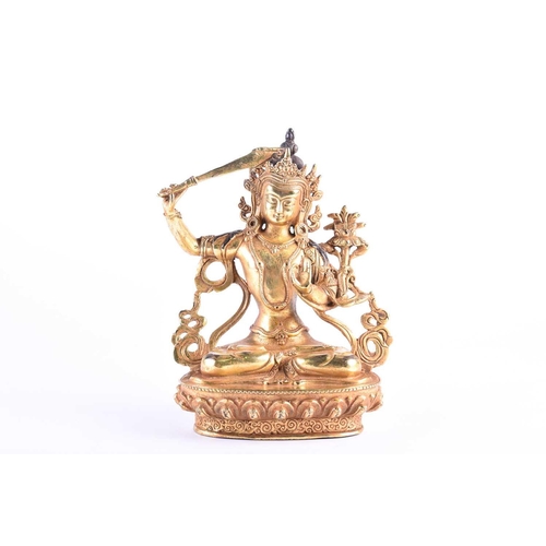 191 - A Sino Tibetan style gilt bronze figure of Manjushri, the left hand in Gyan mudra, on a lotus petal ... 