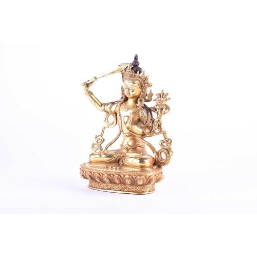 191 - A Sino Tibetan style gilt bronze figure of Manjushri, the left hand in Gyan mudra, on a lotus petal ... 