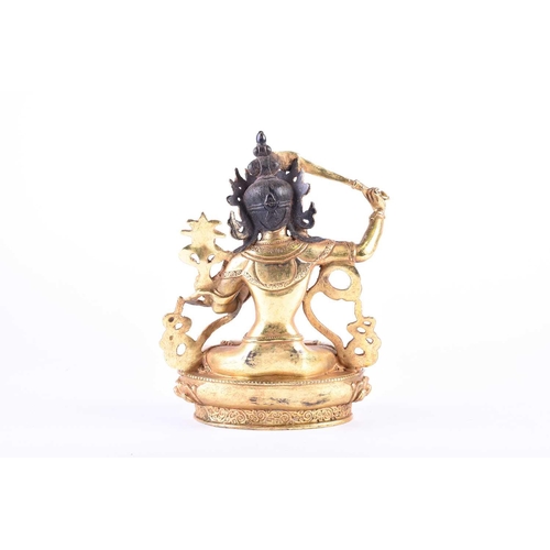 191 - A Sino Tibetan style gilt bronze figure of Manjushri, the left hand in Gyan mudra, on a lotus petal ... 