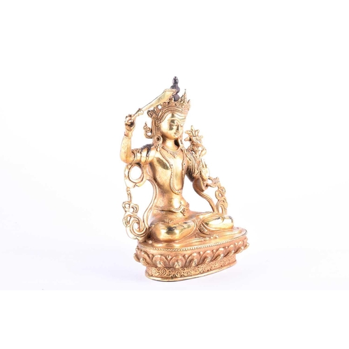 191 - A Sino Tibetan style gilt bronze figure of Manjushri, the left hand in Gyan mudra, on a lotus petal ... 