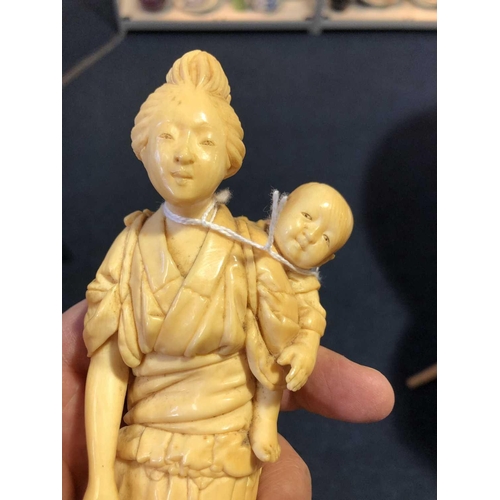 209 - A Japanese ivory okimono, Meiji period, carved as a mother and child, a basket in her right hand, si... 