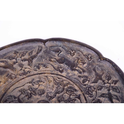 213 - A Chinese bronze mirror, Tang Dynasty, of octagonal lobed form, cast with central pierced raised bos... 