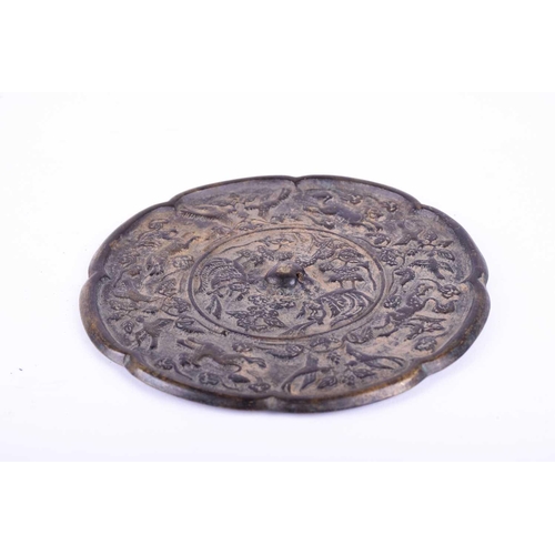 213 - A Chinese bronze mirror, Tang Dynasty, of octagonal lobed form, cast with central pierced raised bos... 