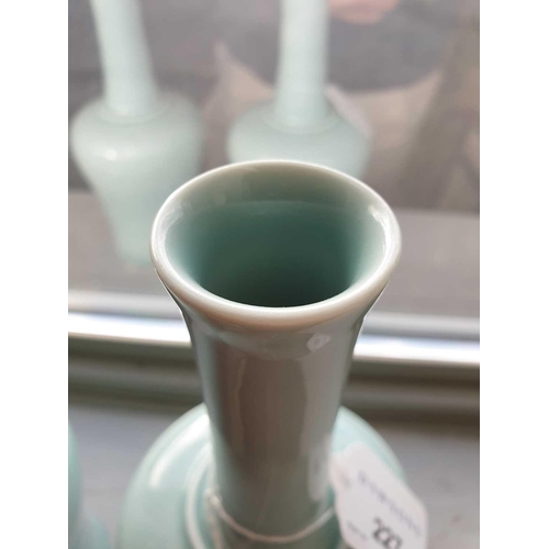 219 - A pair of Chinese celadon mallet shape vases, each with a slightly flared rim on a slender neck term... 