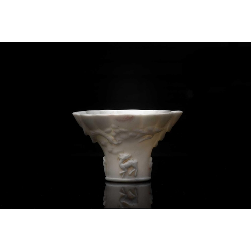 221 - A Chinese blanc de Chine cup, 18th century, modelled as a rhinoceros horn libation cup with scallope... 