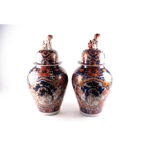 231 - A pair of large Arita imari vases and covers, mid 19th century, each baluster body densely decorated... 