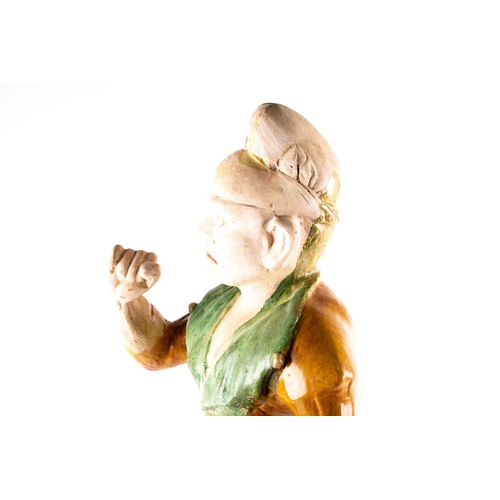 244 - A Chinese Sancai glazed pottery figure of a Western groom, Tang dynasty, modelled standing, his face... 