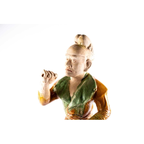 244 - A Chinese Sancai glazed pottery figure of a Western groom, Tang dynasty, modelled standing, his face... 