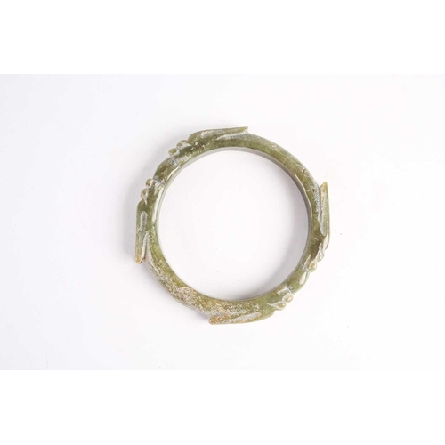 273 - A Chinese spinach green jade bangle, Warring States period, with four opposing dragons with long ear... 