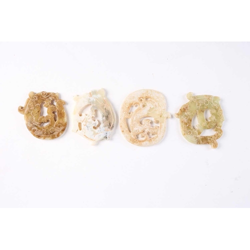 279 - Four Chinese jade amulets, Warring States period, each carved as a coiling dragon, the stones from g... 