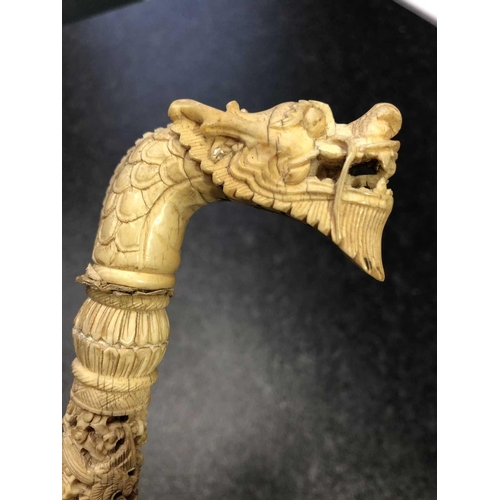 312 - A Chinese carved ivory parasol handle, early 20th century, the terminal carved as a dragons head, th... 