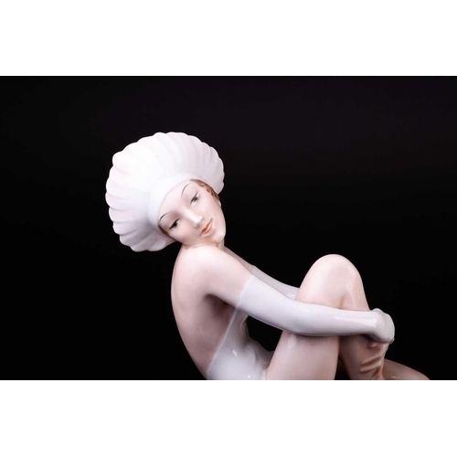 387 - A Rosenthal figure, circa 1930s, modelled as a young woman seated on a pedestal wearing a white bath... 