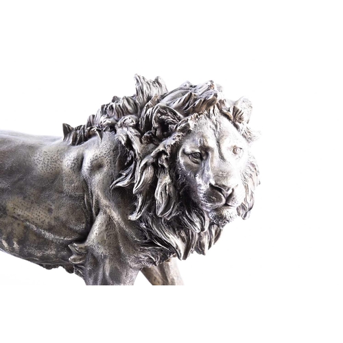 415 - A cast nickel lion, 20th century, modelled standing, on a black marble base, 49cm wide, 30cm high