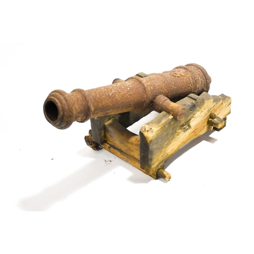 443 - A 19th century cast iron model of a naval cannon, 84 cm long, mounted to a wooden carriage (a/f).