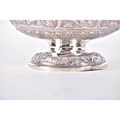 547 - A 20th century Burmese white metal pedestal bowl typically decorated with a figures and trees in rel... 