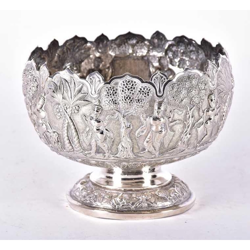 547 - A 20th century Burmese white metal pedestal bowl typically decorated with a figures and trees in rel... 