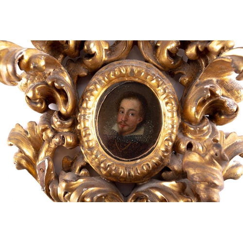 57 - A 17th century oval miniature portrait of a nobleman, painted on wood, in an elaborate scrolling gil... 