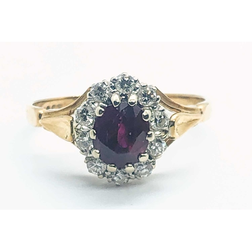 581A - An 18ct yellow gold, diamond, and ruby cluster ring, set with a mixed oval-cut ruby, within a border... 