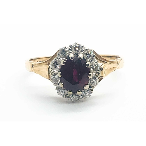 581A - An 18ct yellow gold, diamond, and ruby cluster ring, set with a mixed oval-cut ruby, within a border... 