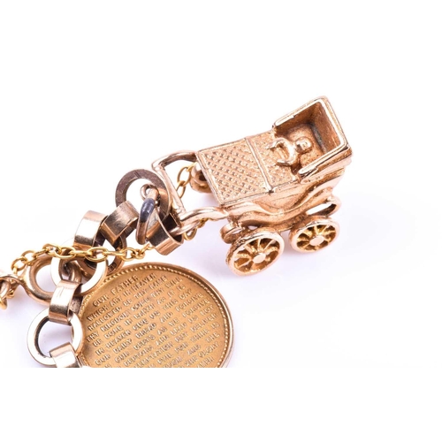 601 - A 9ct yellow gold charm bracelet, suspended with various charms including a pram, a Paris charm, a d... 