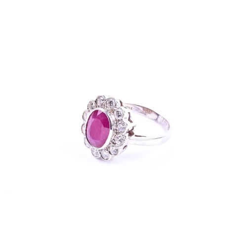 615 - An 18ct white gold, diamond, and ruby cluster ring, set with a mixed oval-cut ruby of approximately ... 