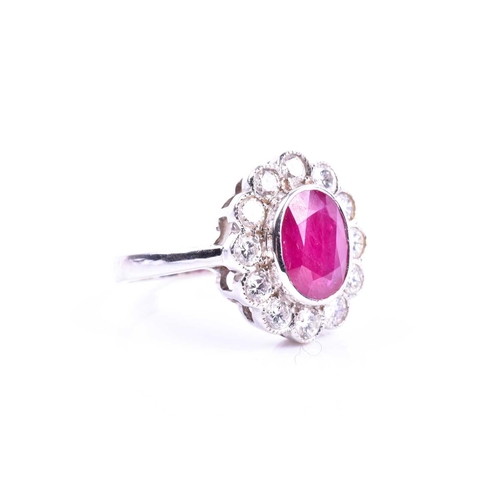 615 - An 18ct white gold, diamond, and ruby cluster ring, set with a mixed oval-cut ruby of approximately ... 