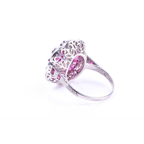 616 - An unusual platinum, diamond, and ruby cocktail ring, centred with a mixed oval-cut ruby, within a b... 