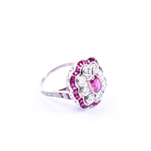 616 - An unusual platinum, diamond, and ruby cocktail ring, centred with a mixed oval-cut ruby, within a b... 