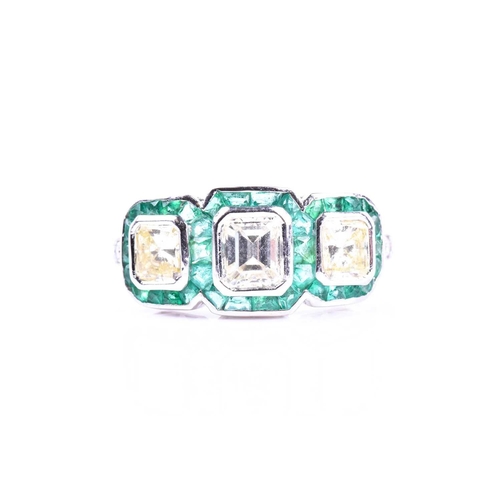 631 - A diamond and emerald ring, set with an emerald-cut diamond flanked with two mixed square-cut diamon... 