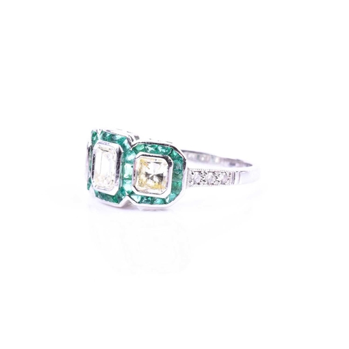 631 - A diamond and emerald ring, set with an emerald-cut diamond flanked with two mixed square-cut diamon... 