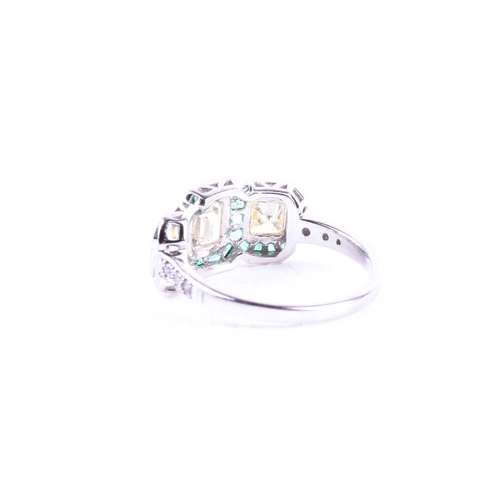 631 - A diamond and emerald ring, set with an emerald-cut diamond flanked with two mixed square-cut diamon... 