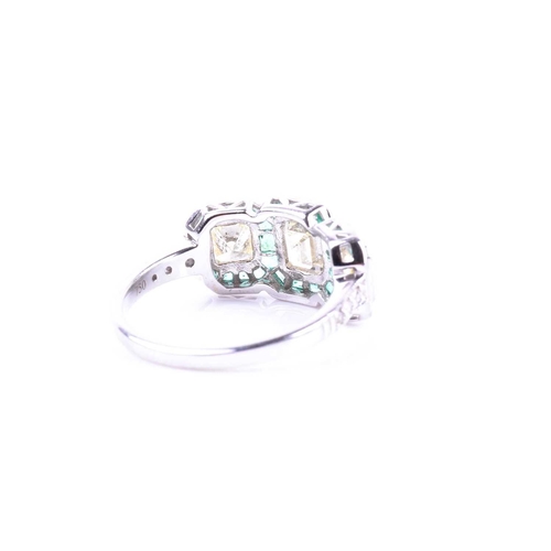 631 - A diamond and emerald ring, set with an emerald-cut diamond flanked with two mixed square-cut diamon... 